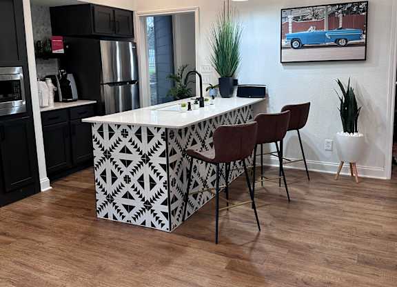 a kitchen with a large white island with a black and white geometric pattern