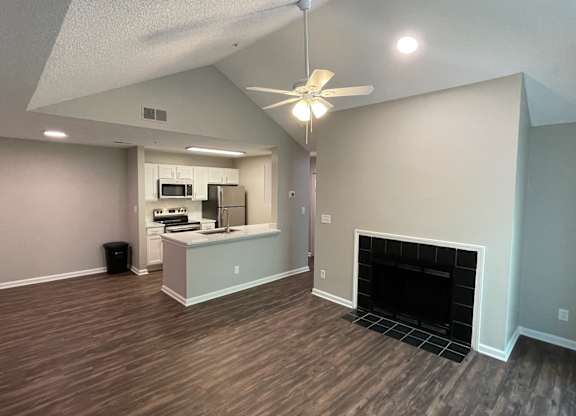 a living room with a fireplace and a kitchen in the background