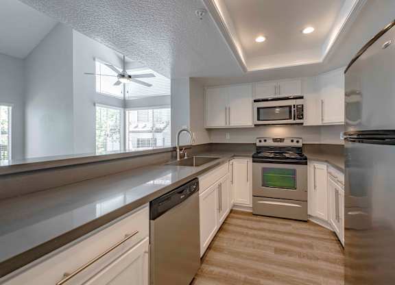 Apartments for Rent in San Clemente - Rancho Del Mar - Kitchen with Stainless Steel Appliances, Hardwood-Inspired Flooring, and White Cabinetry