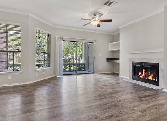 Pet Friendly Apartments in Plano, TX - Carrington Park Apartments Living Room With Fireplace, Ceiling Fan, Hardwood Style Flooring and Access to Outside Patio With Sliding Glass Door