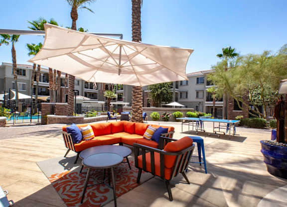 1-Bedroom Apartments in North Phoenix, AZ - Winding Brook - Courtyard with Shaded Area, Outdoor Couch, Armchair, Coffee Table, Pam Trees, and Ping-pong Table.