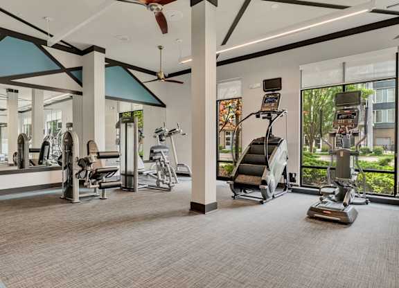 a gym with exercise equipment and windows at the estates apartments