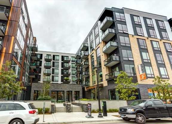 A modern apartment complex with cars parked in front.