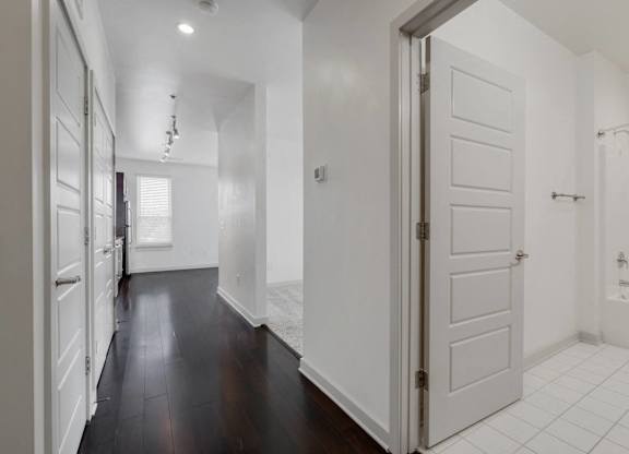 a renovated living room and kitchen with white walls and wood floors