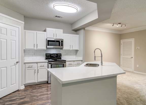 Woodstock, GA Apartments – Lea Woodstock – Luxury kitchen with quartz counter tops, white cabinets, stainless-steel appliances and hardwood floors