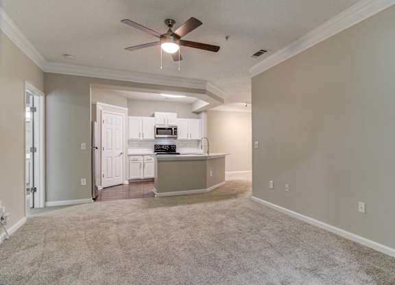 Woodstock, GA Apartments – Lea Woodstock – Living room with plush carpeting, ceiling fan and view of kitchen