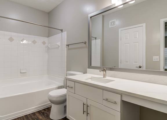 Pet-Friendly Apartments in Woodstock, GA – Lea Woodstock – bathroom with white cabinets, quartz counter tops, a toilet and a tub/shower