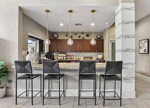 A kitchen with a bar area and four black chairs.