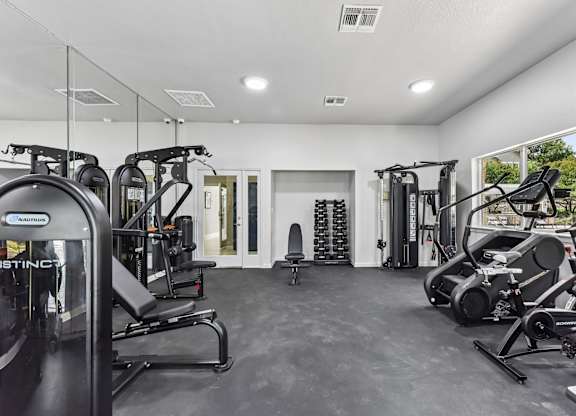A spacious gym with a variety of equipment including treadmills, stationary bikes, and weight machines.