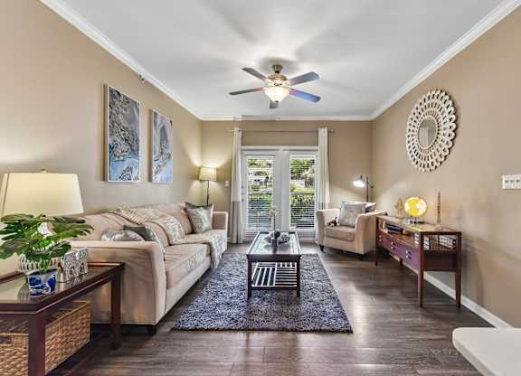A well-lit living room with a sofa, a coffee table, and a ceiling fan.