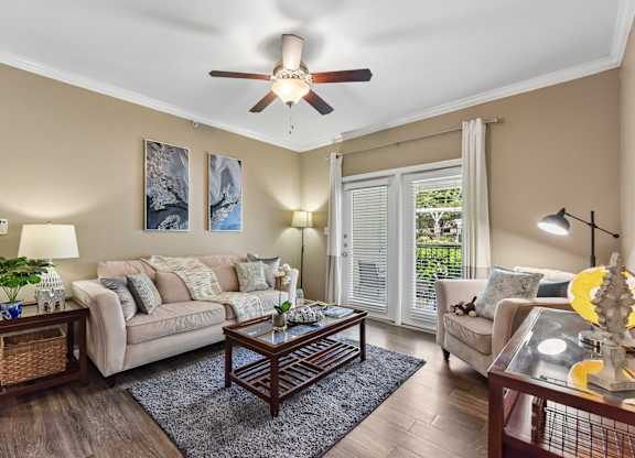A living room with a couch, a coffee table, and a ceiling fan.