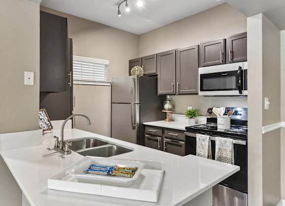 A kitchen with a white counter top and a sink.