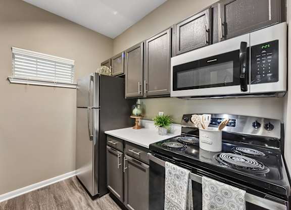A kitchen with a black stove top oven and a black microwave above it.