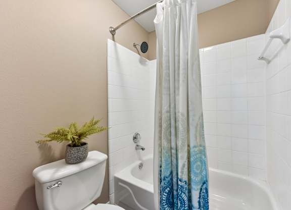 A white toilet sits next to a bathtub with a blue shower curtain.
