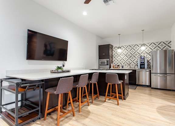 A kitchen with a white counter top and brown chairs.