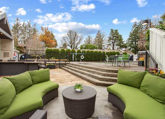 A patio with green couches and a table with a plant on it.