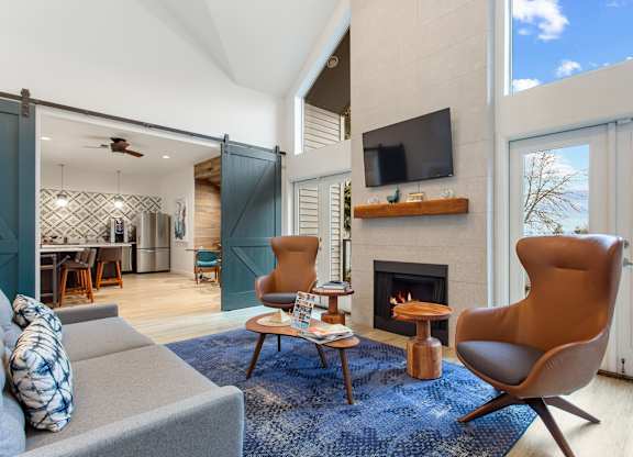 A living room with a grey couch, a brown chair, and a fireplace.