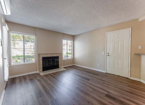 an empty living room with wood flooring and a fireplace