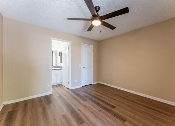 an empty living room with wooden floors and a ceiling fan