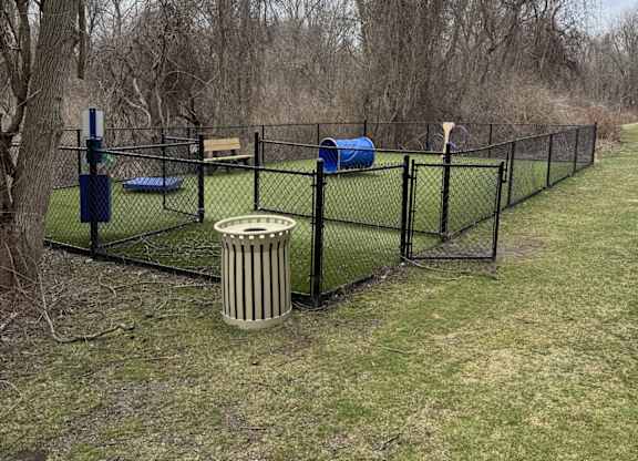 A fenced area with a blue object and a trash can.