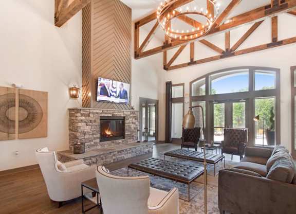 A modern living room with a stone fireplace and a large chandelier.