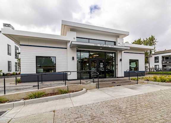 A white building with a black railing in front.