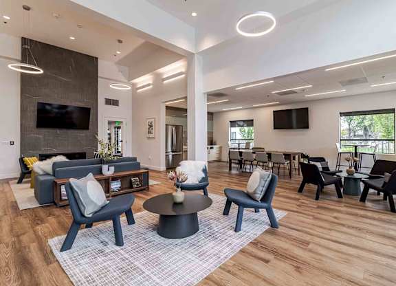 A modern living room with a grey rug and black chairs.