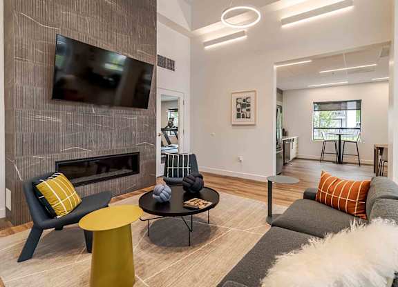 A modern living room with a grey couch, a yellow chair, and a fireplace.
