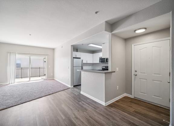 an empty living room and kitchen with a door to a balcony