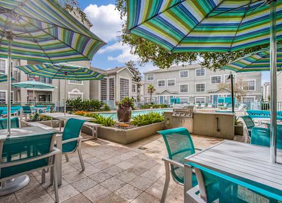 Luxury 2-Bedroom Apartments in Houston, TX - The Maroneal - BBQ/Picnic Area with Tables, Chairs, Umbrellas, a Grilling Station, and a View of the Pool