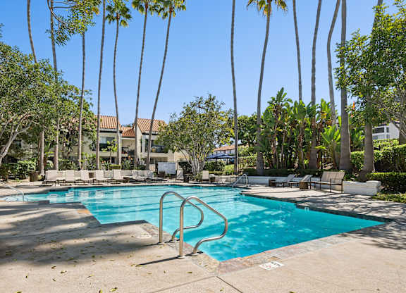 A swimming pool surrounded by palm trees and lounge chairs.