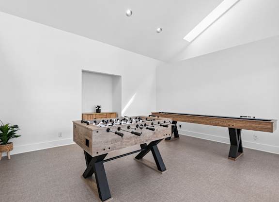 A foosball table sits in a room with a potted plant and a window.