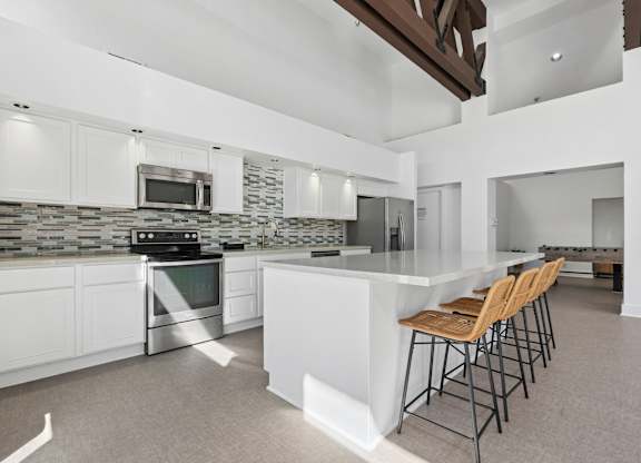 A modern kitchen with white cabinets and a stone backsplash.