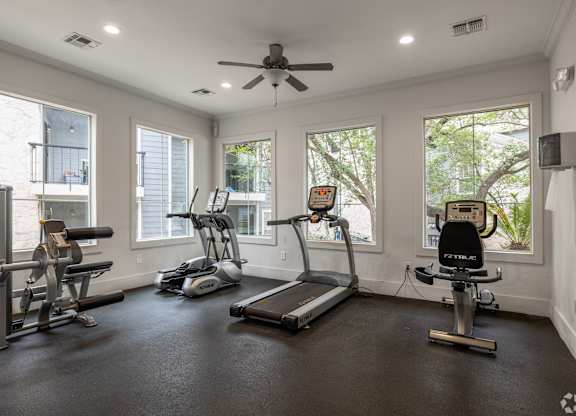 A spacious home gym with a treadmill, elliptical machines, and a stationary bike.