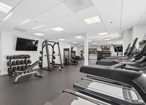A gym with a variety of equipment including treadmills, weights, and exercise machines.