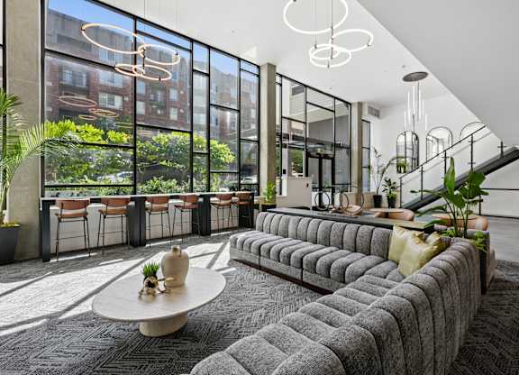 A modern living room with a large grey sofa and a round table with a vase on it.
