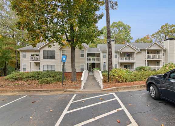 A car is parked in a parking lot in front of apartment buildings.