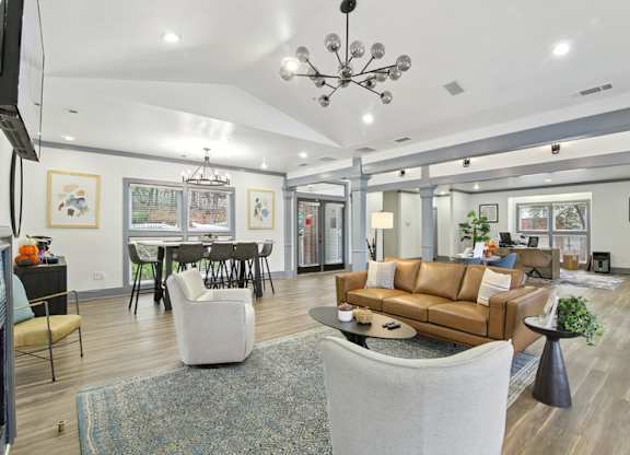 A living room with a brown couch and a chandelier.