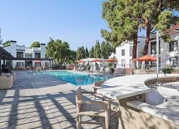 A pool area with chairs and trees in the background.