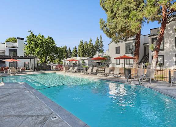 A swimming pool surrounded by trees and chairs.