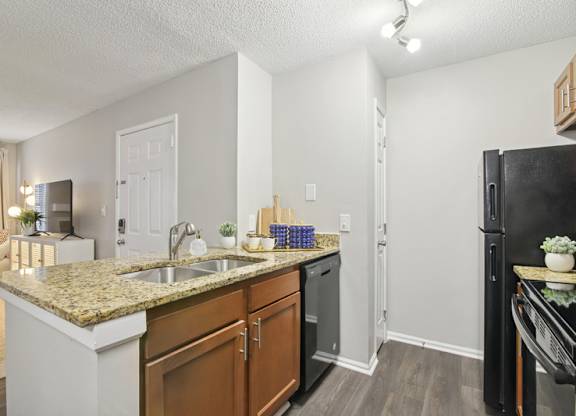 A kitchen with a granite countertop and a black refrigerator.
