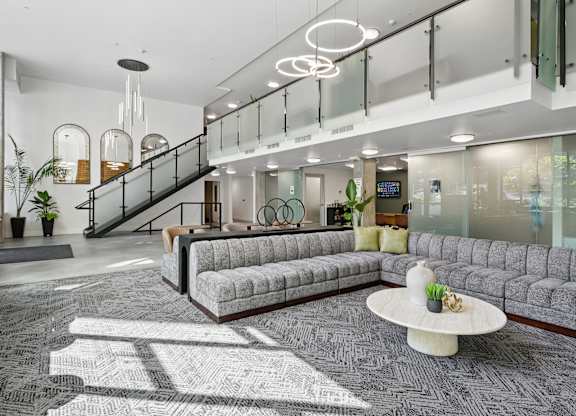 A modern office lobby with a staircase, couches, and a coffee table.