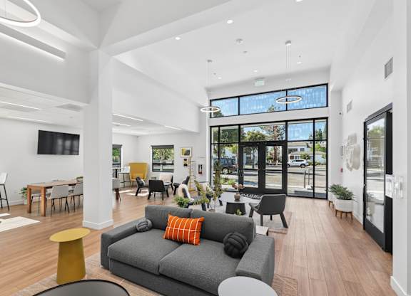A modern living room with a grey couch and a yellow stool.