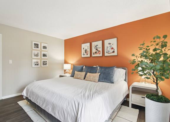 A bedroom with a bed, nightstand, and pictures on the wall.