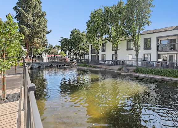 A canal with a wooden walkway on the left and houses on the right.