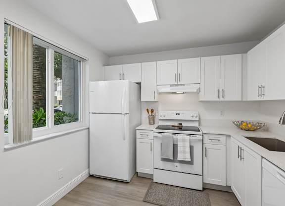 A white kitchen with a refrigerator, oven, and sink.