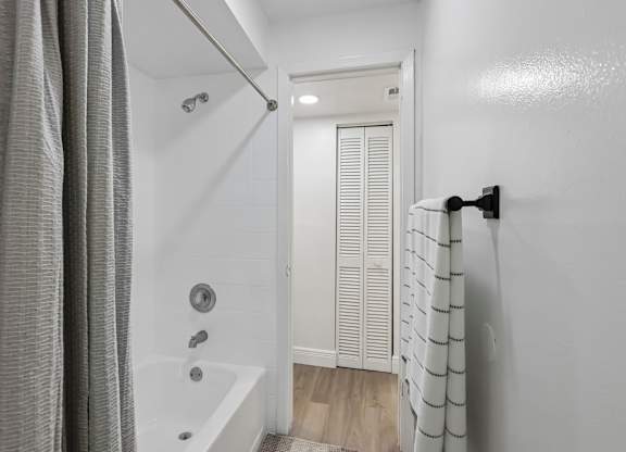 A white bathroom with a shower curtain and a white door.