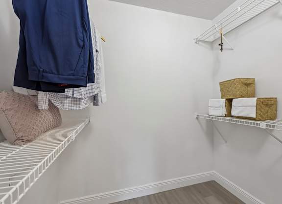 A white closet with a shelf and a hanging coat.