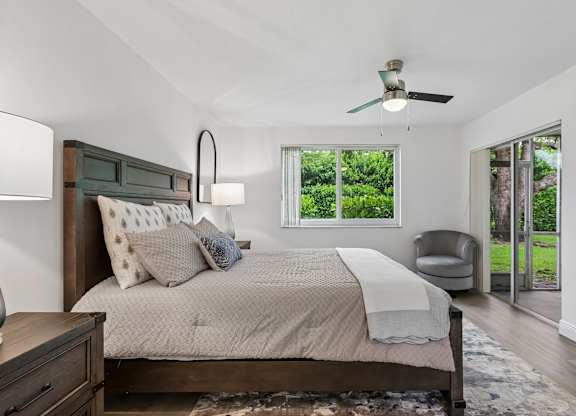 A bedroom with a bed, chair, and a ceiling fan.
