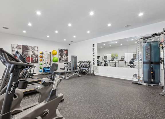 A gym with a row of treadmills and a row of exercise bikes.